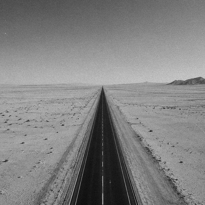 A long, straight desert highway running to the horizon
