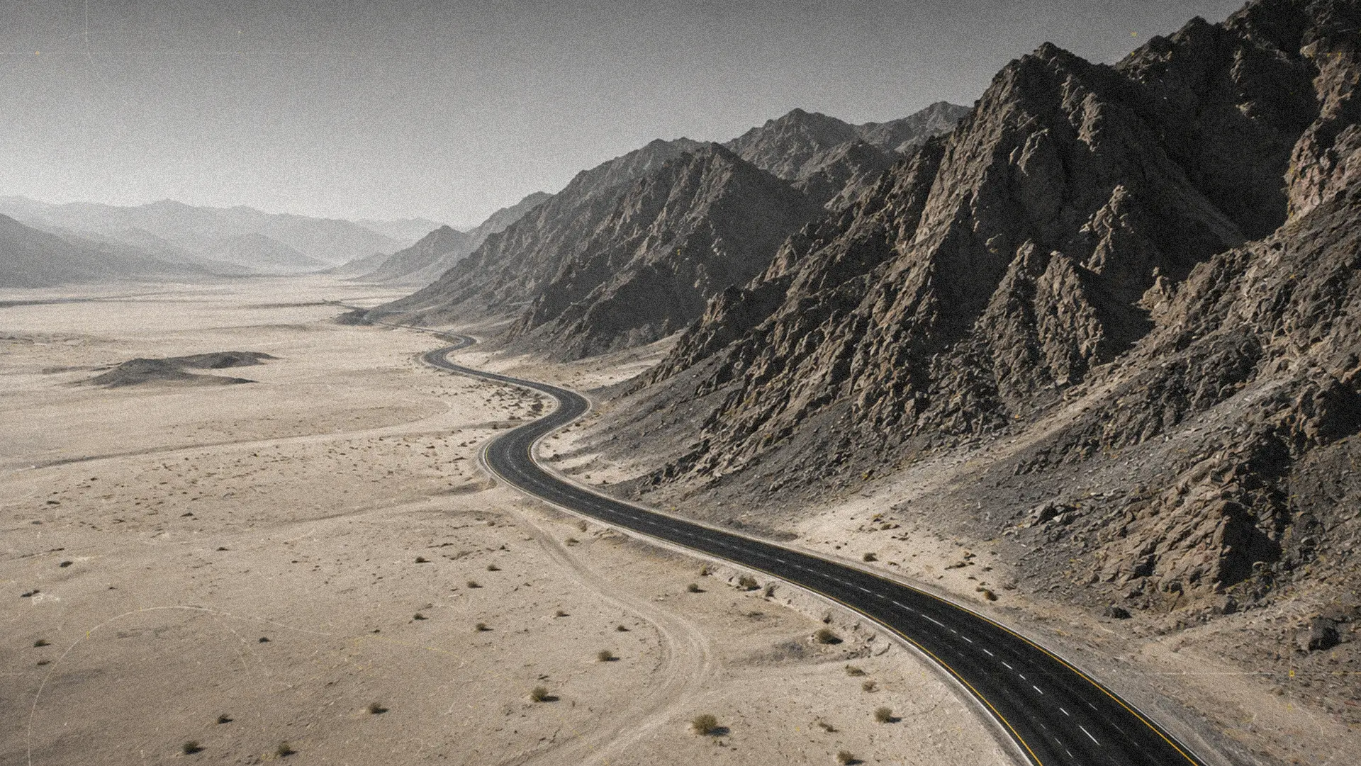 Winding desert road cutting through arid mountain terrain